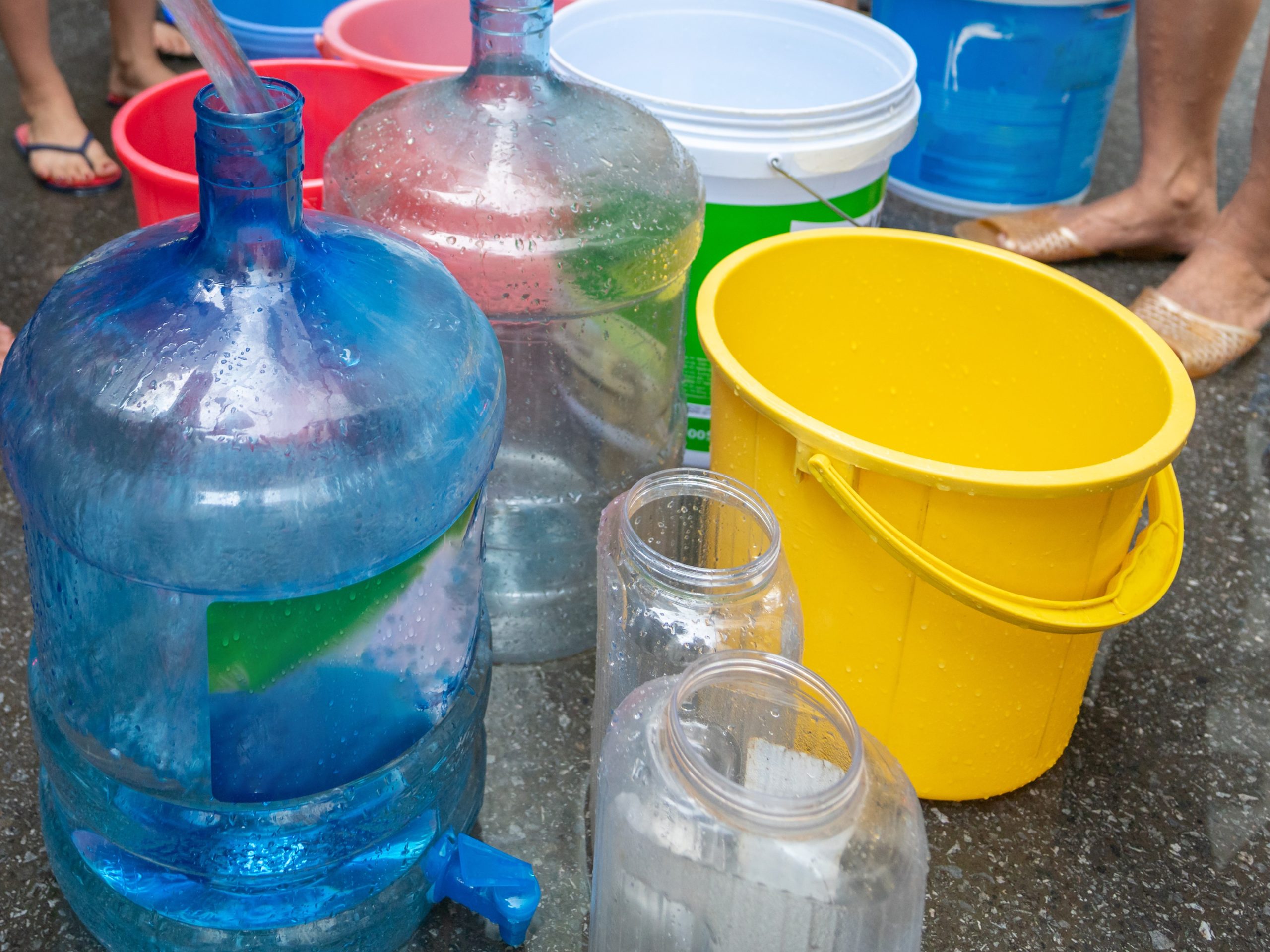 Empty water buckets waiting for fresh water from emergency mobile tank truck La zeolita como filtro de agua